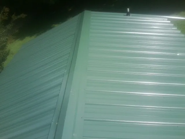 New green metal panels meeting at the ridge of a roof — Flat Roof Repair work by our crew in Titusville