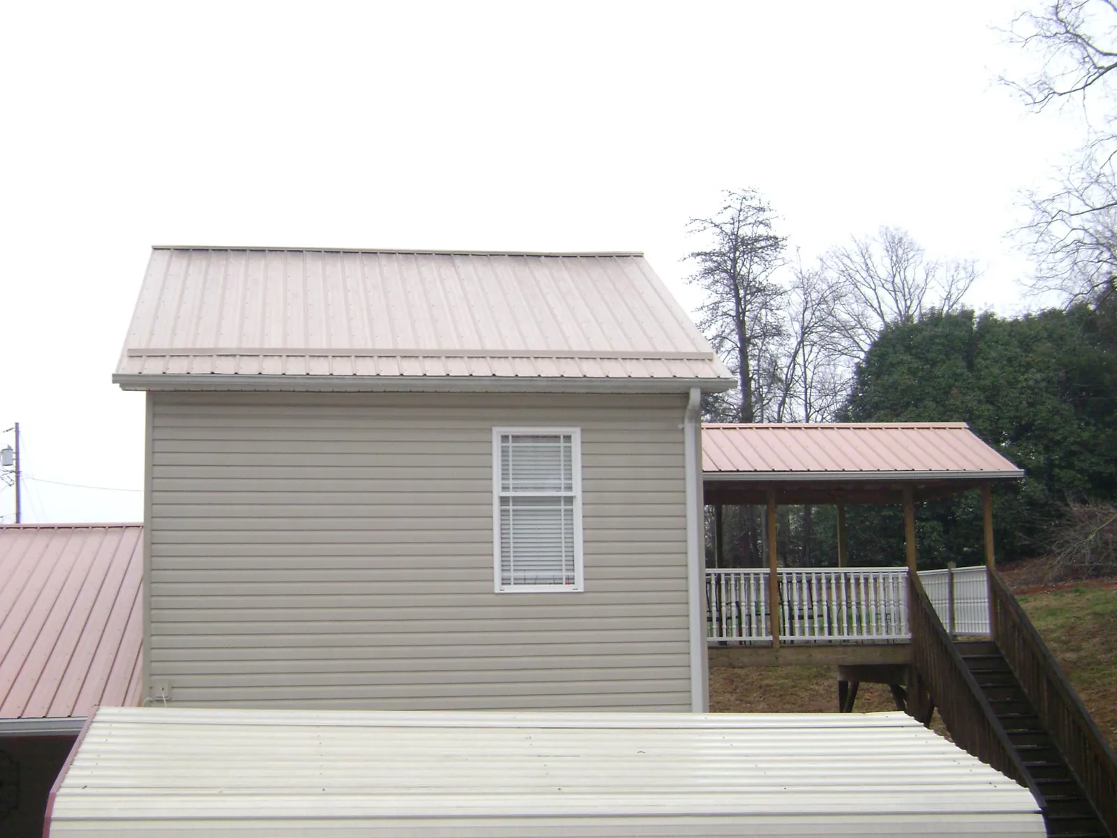 Tan metal roofs on a two story addition and attached porch, from a Roof Replacement job in Titusville